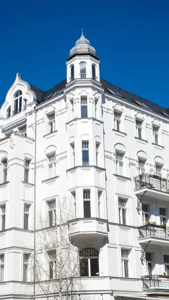 Weißes historisches Gebäude mit verzierten Balkonen und einer kleinen Kuppel vor einem strahlend blauen Himmel - ein außergewöhnlicher Fund auf Immopromotion.